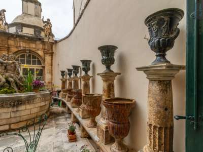 Lungo il perimetro 12 colonnine reggono altrettanti vasi in ceramica con figure classicheggianti, alternati ad altri in pietra